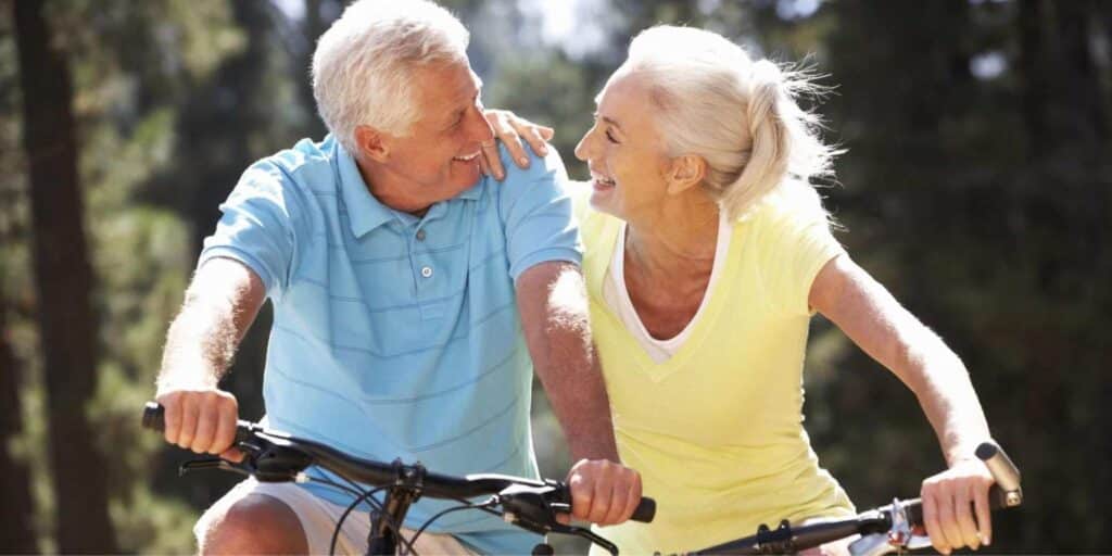An older couple riding a bike and smiling