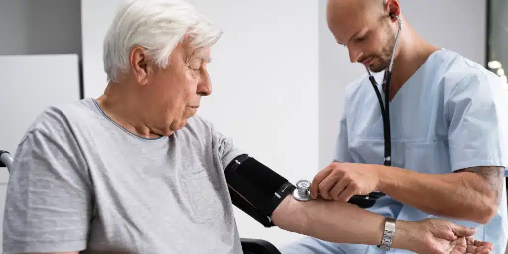 Older man getting his pulse checked by a male doctor