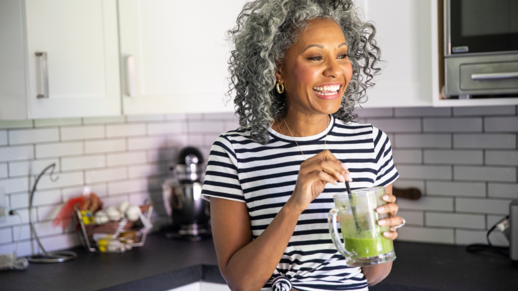 woman smiling about to eat green blended drink